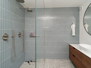 A bathroom with a shower, a sink, and a mirror.