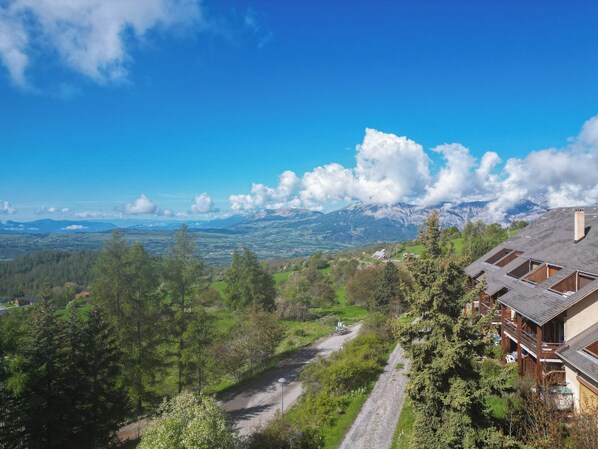 A mountain view with a road leading to a building with multiple rooms and a balcony.