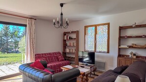 Un salon avec un canapé, une table basse, un téléviseur et une bibliothèque.