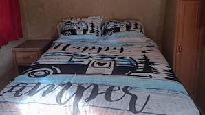 A bedroom with a bed featuring a camper van design, a red curtain, a wooden nightstand, and an air conditioning unit on the wall.