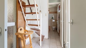 A compact bathroom with a wooden chair, a white toilet, and a small sink. - Holiday Home Zeeland Near Westerschelde (Baarland)