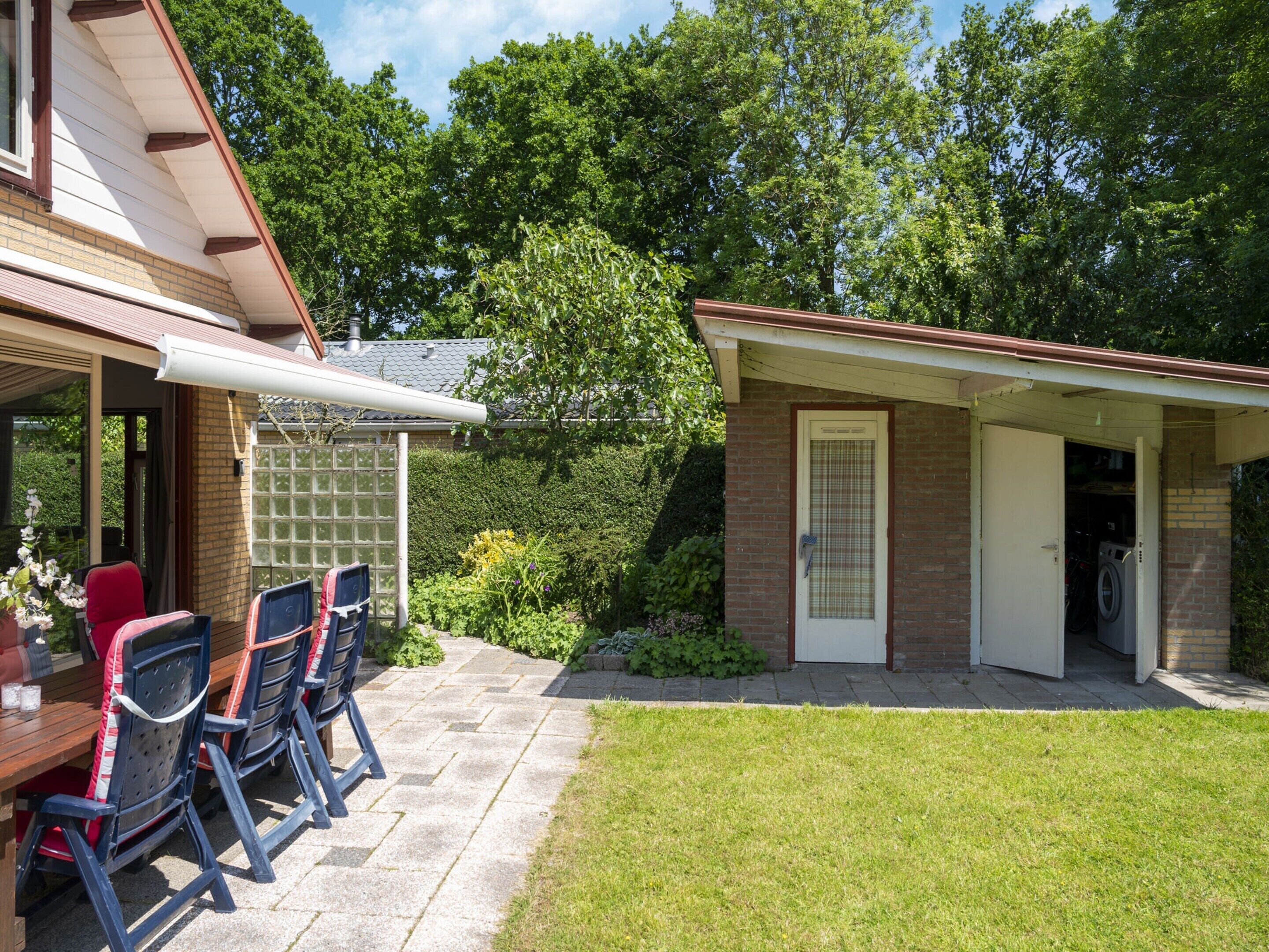 A patio with outdoor seating and a small building with a door and a washing machine inside.