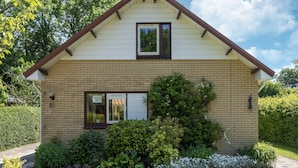 A two-story house with a brick facade, a front porch, and a small garden area. - Holiday Home Zeeland Near Westerschelde (Baarland)