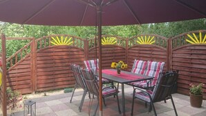An outdoor patio with a table and chairs, a large umbrella, and a decorative fence. - Holiday Apartment Red Milan (Bobitz)