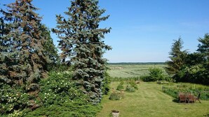 A grassy outdoor area with trees, a small garden, and a wooden bench. - Holiday Apartment Red Milan (Bobitz)