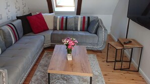 A modern living room with a grey sectional sofa, a wooden coffee table, and a small side table. - Holiday Apartment Red Milan (Bobitz)