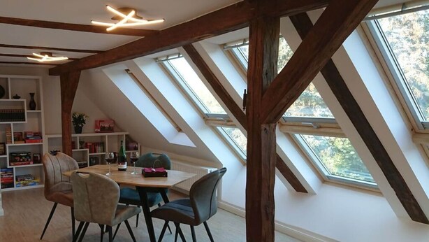 A dining area with a wooden table and chairs, a bookshelf, and skylights. - Holiday Apartment Red Milan (Bobitz)