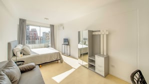 Ein modernes Schlafzimmer mit Bett, einer Couch, einem Spiegel und einem Fernseher.