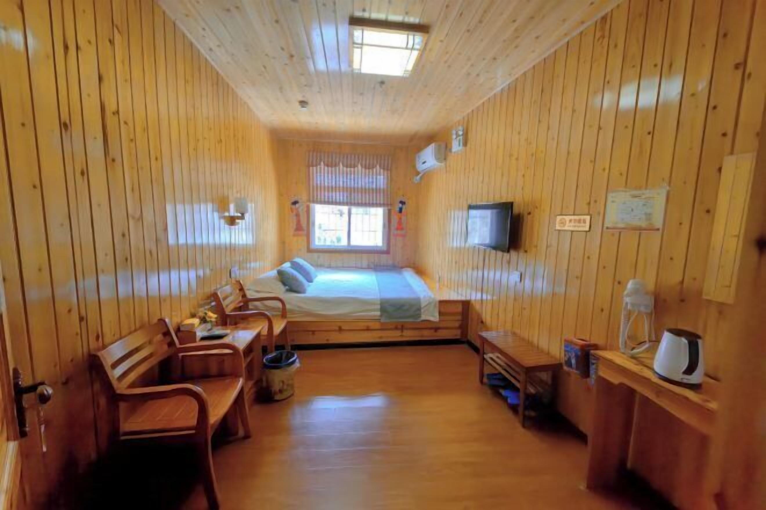 Une cabane en bois comprenant un lit, un coin salon et un téléviseur.