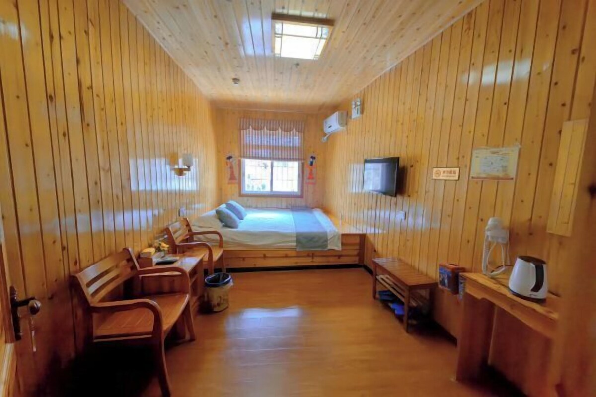 Eine Holzhütte mit einem Bett, einer Sitzecke und einem Fernseher.
