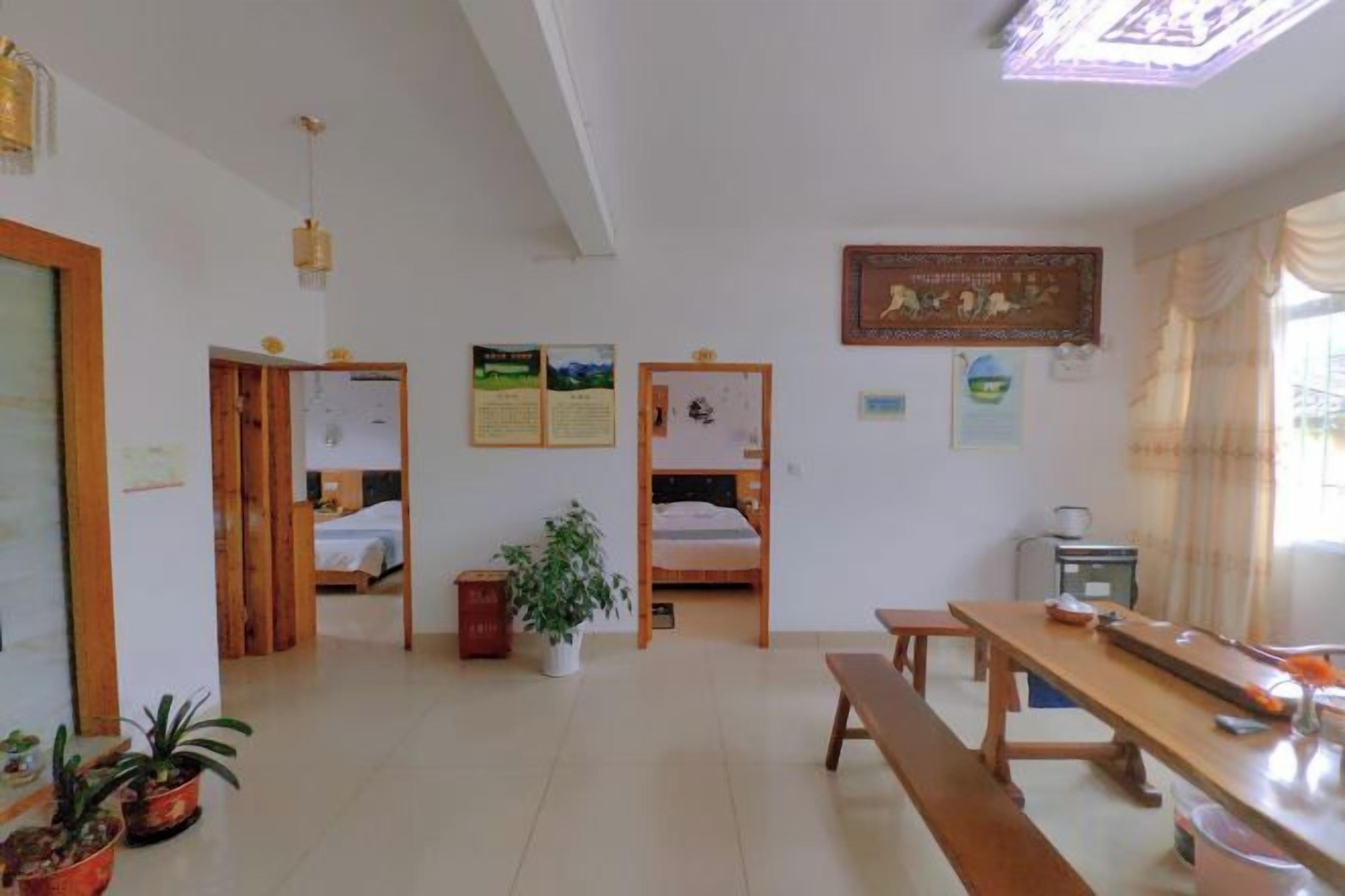 A room with a wooden bench, a table, and two beds with wooden frames.