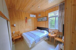 A wooden-paneled room with a bed, a small table, a chair, and a window. - Nanjing Sister Inn (Nanjing County)