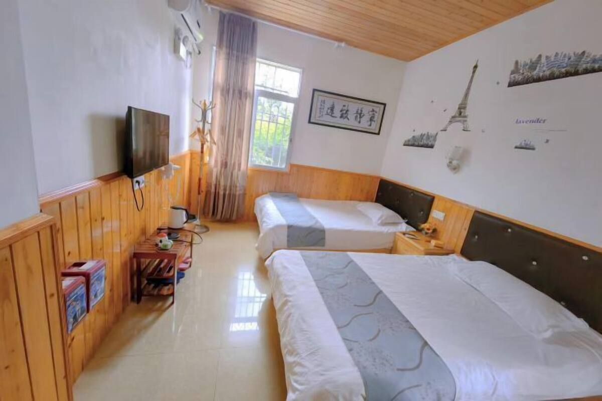 Habitació d'hotel amb dos llits, televisió, escriptori de fusta i finestra amb cortines.