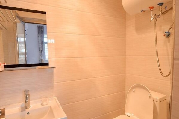 A bathroom with a sink, mirror, toilet, and shower. - Nanjing Sister Inn (Nanjing County)