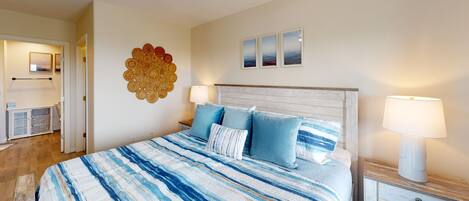Un dormitorio con cama, una mesita de noche, una lámpara, una obra de arte en la pared y vistas al mar.