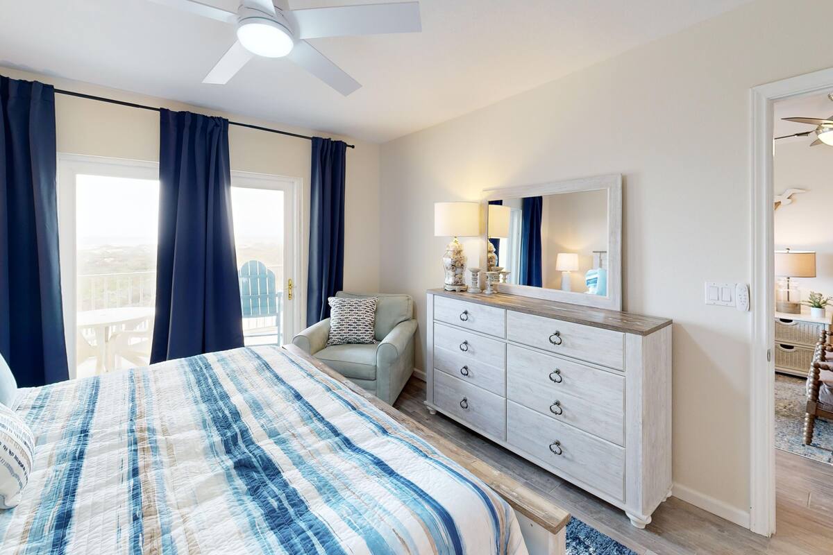 A bedroom with a bed, a dresser, a chair, and a ceiling fan.