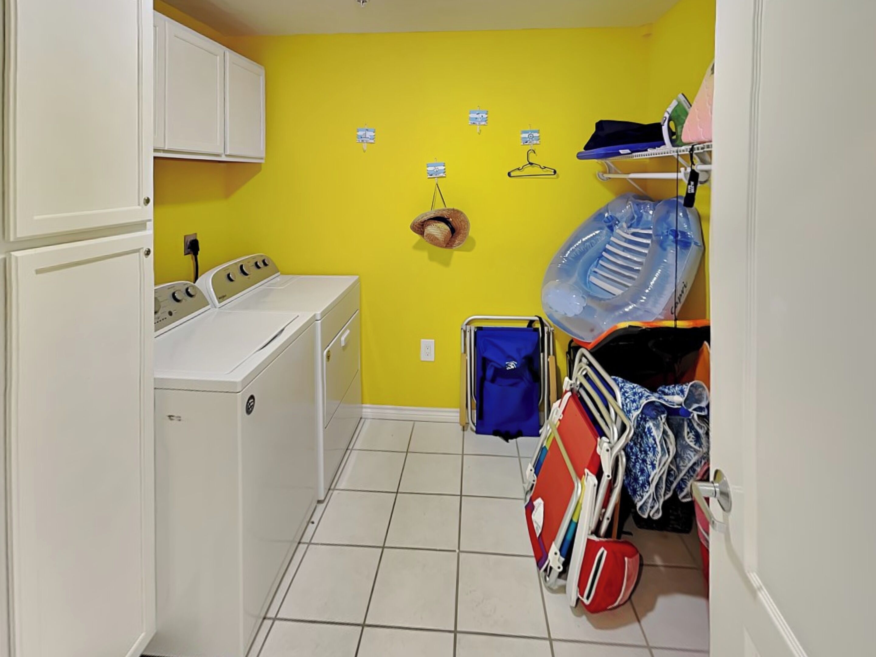 A laundry room with a washing machine, a drying rack, and a cart with cleaning supplies.