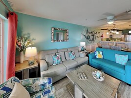 A living room with a teal wall, a grey sofa, a blue sofa, and a wooden coffee table.