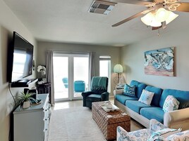 A living room with a television, a sofa, a coffee table, and a painting on the wall.