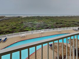 A pool area with a view of the ocean and a beach.