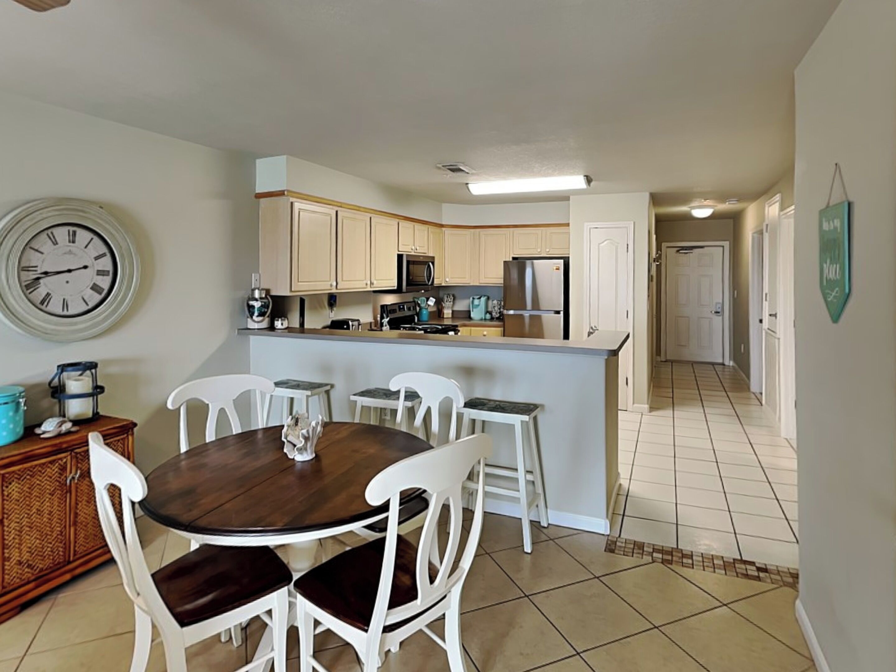 A compact kitchen with white cabinets, a central island, and a dining area with white chairs.