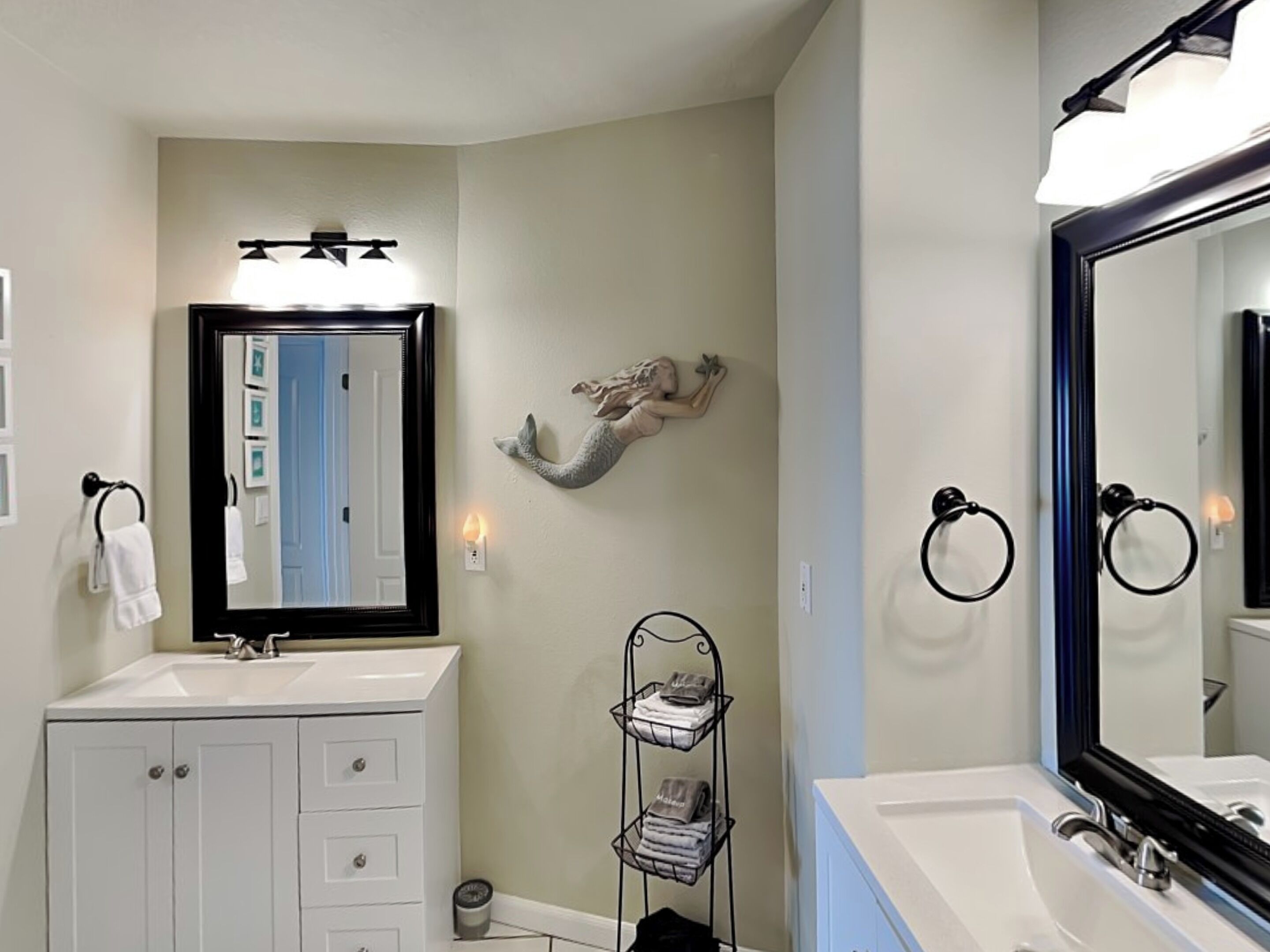 A bathroom with two sinks, a large mirror, and a towel rack.