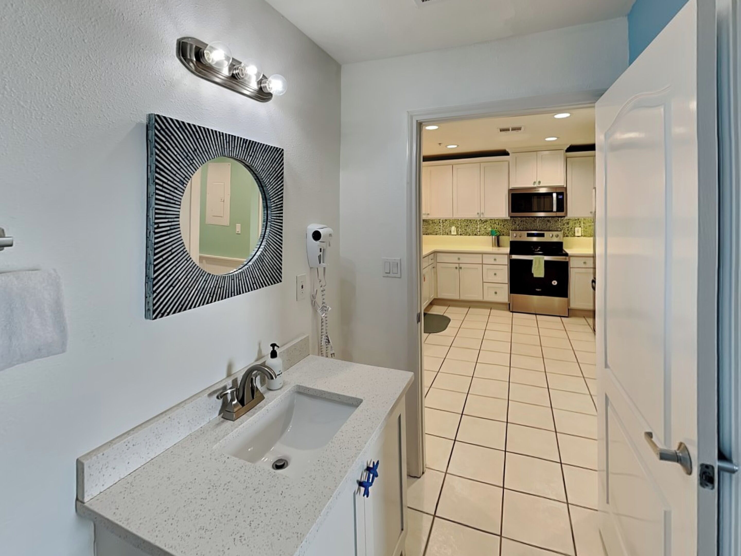 A bathroom with a double sink, a mirror with a black frame, and a hairdryer on the wall.