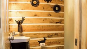 Un baño con paneles de madera, un lavamanos, un inodoro y una ducha.