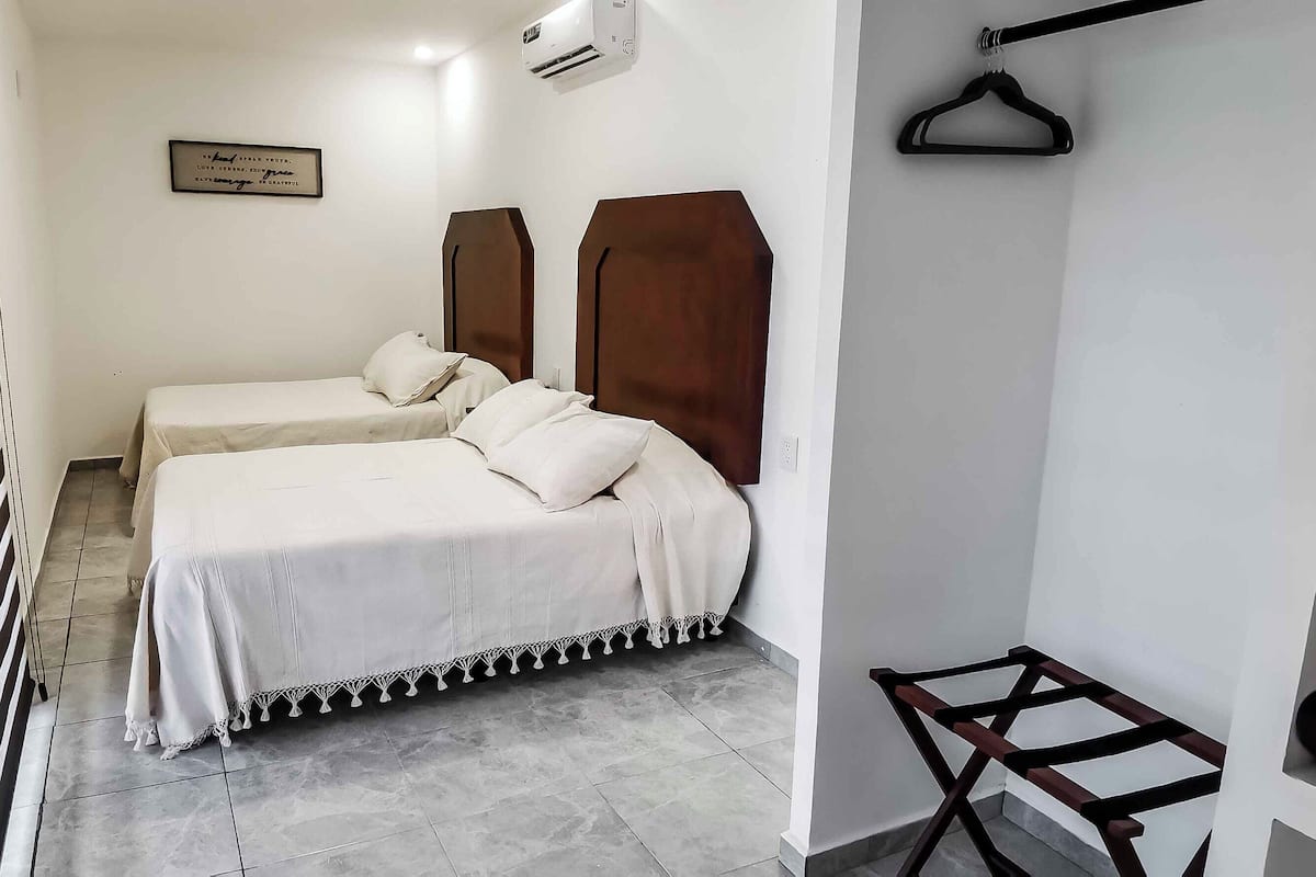 A hotel room with two beds, a wooden headboard, a framed quote on the wall, and a hanging rack.