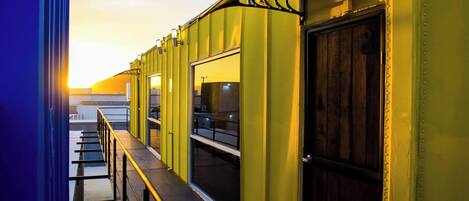 A corridor with yellow walls, a wooden door, and a window.