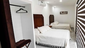 Habitación de hotel con dos camas, cabecera de madera, aire acondicionado de pared y un cartel que dice 'Thankful'.