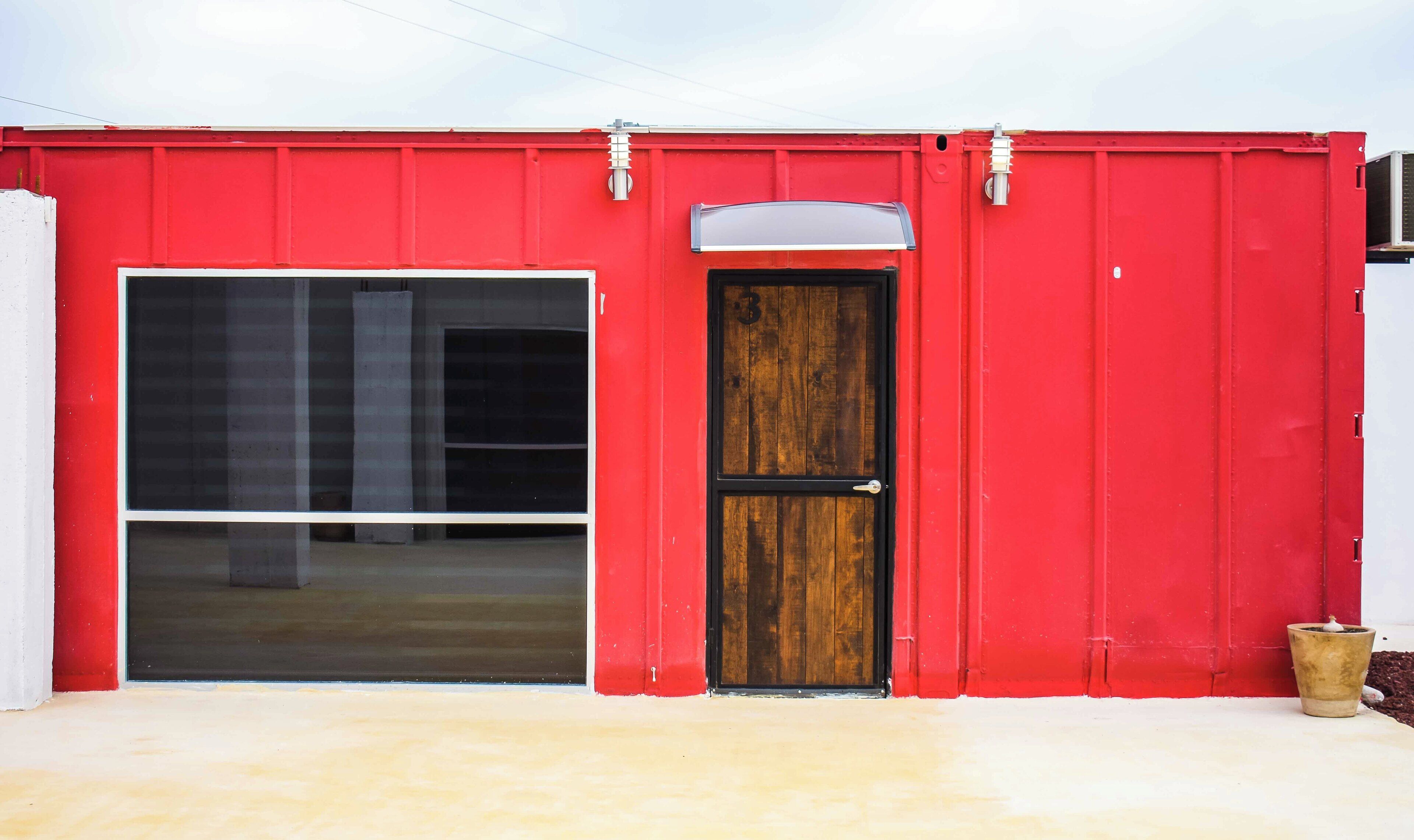 A red building with a large garage door and a smaller wooden door.