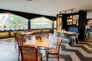 Un restaurante con una decoración moderna, que ofrece una variedad de opciones de asientos, incluyendo mesas y cabinas, y grandes ventanales con vistas al exterior.