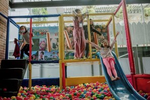 Children playing on a playground with a slide and climbing structure.