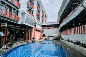 Una piscina interior con vistas a un edificio de varios pisos, un restaurante y una escalera.