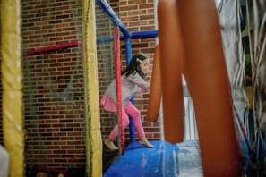 A child playing on a blue trampoline with a brick wall in the background. - The Bountie Hotel & Convention Centre Sukabumi (Cikole)