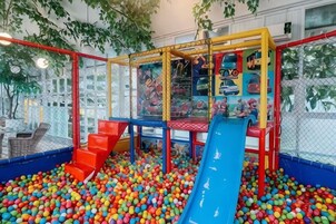 Espaço coberto para brincar com escorrega, piscina de bolinhas e estruturas de escalada.