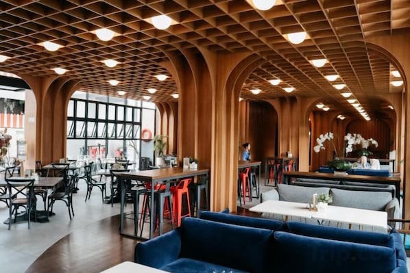 A spacious indoor area with high wooden ceilings, tables, and seating arrangements.