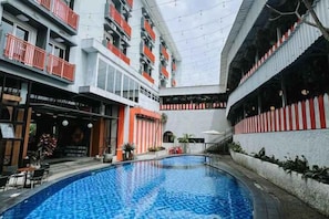 Un hotel con piscina central, balcones y un restaurante.