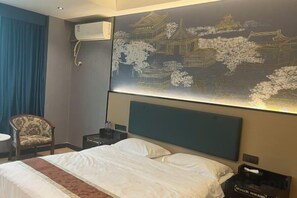 A hotel room with a bed, a chair, a nightstand, and a wall-mounted air conditioner. - Yunjing hotel (Dongguan)