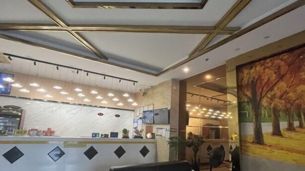 A hotel reception area with a modern design, featuring a reception desk, seating area, and a large painting on the wall. - Yunjing hotel (Dongguan)