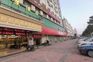 A hotel with a red awning, a visible entrance, and a parked scooter.