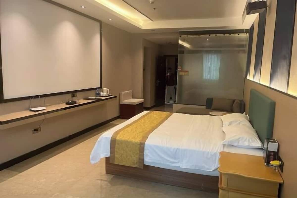 Una habitación de hotel con una cama, una mesita de noche, un escritorio y un espejo grande.