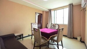 A dining area with a table and chairs, a bench, a door, and a window with curtains. - Yunjing hotel (Dongguan)