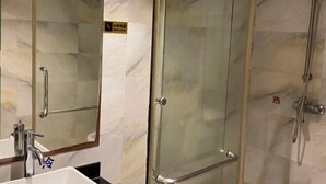 A bathroom with a glass shower enclosure, a sink with a mirror, and a faucet. - Yunjing hotel (Dongguan)