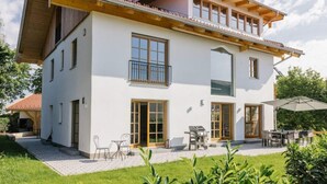 A two-story house with a patio area, a grill, and outdoor seating. - Cloud 9A Comfortable Holiday Residence (Traunstein)