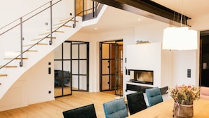 A modern interior with a wooden dining table, black chairs, a staircase, and a fireplace. - Cloud 9A Comfortable Holiday Residence (Traunstein)