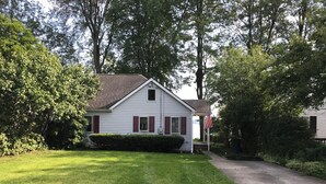 A single-story house with a sloped roof, a front porch, and a well-maintained lawn. - North Shore, Conesus Lake (Lakeville)