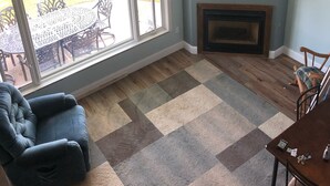 A living room with a large window, a flat-screen TV, a fireplace, and a cozy seating area. - North Shore, Conesus Lake (Lakeville)