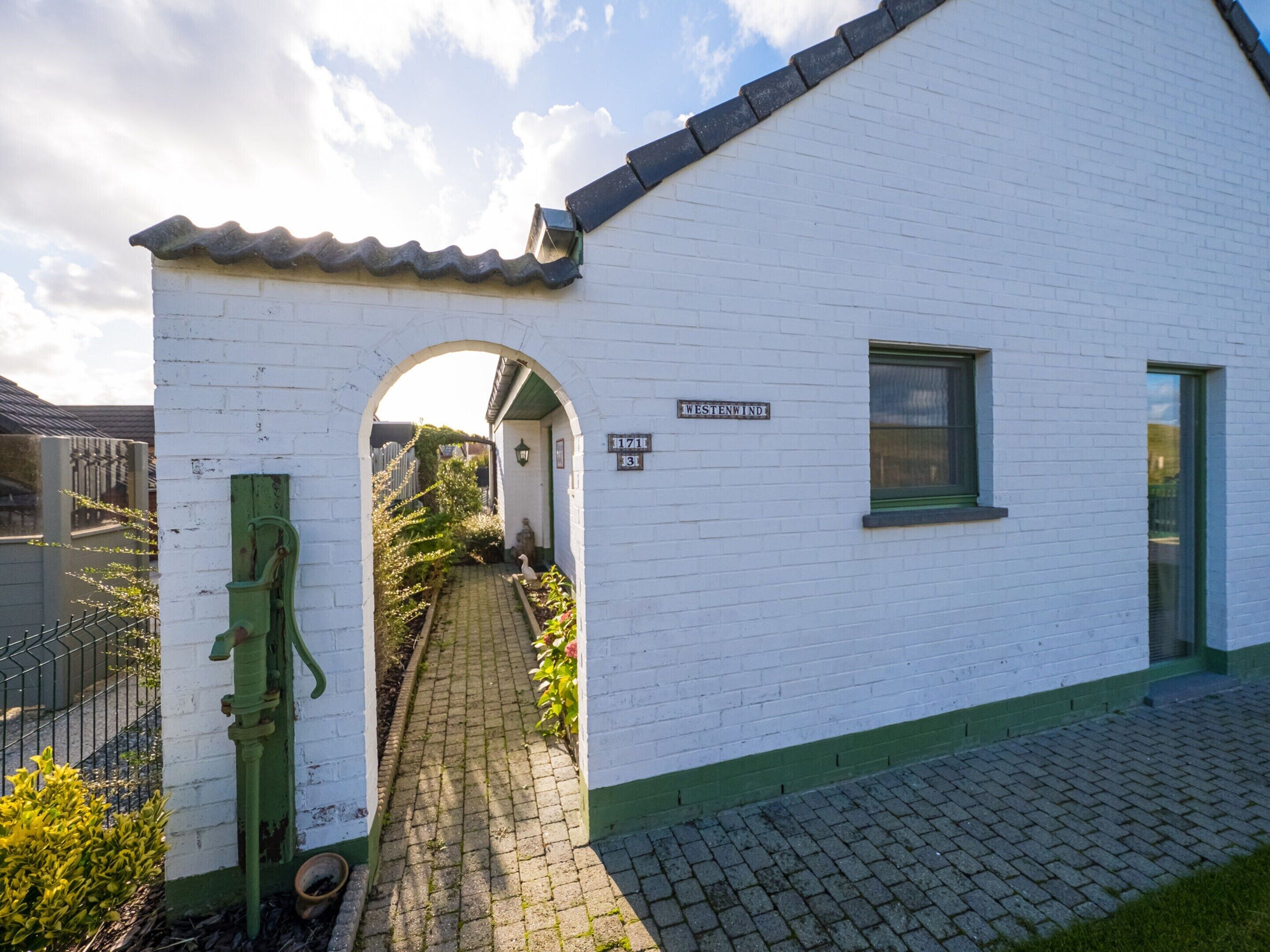 A white building with a green door and a sign reading "WESTENWIND 1171".